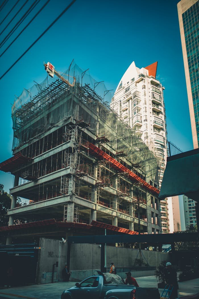 digital High-rise building under construction with scaffolding and crane in urban cityscape.