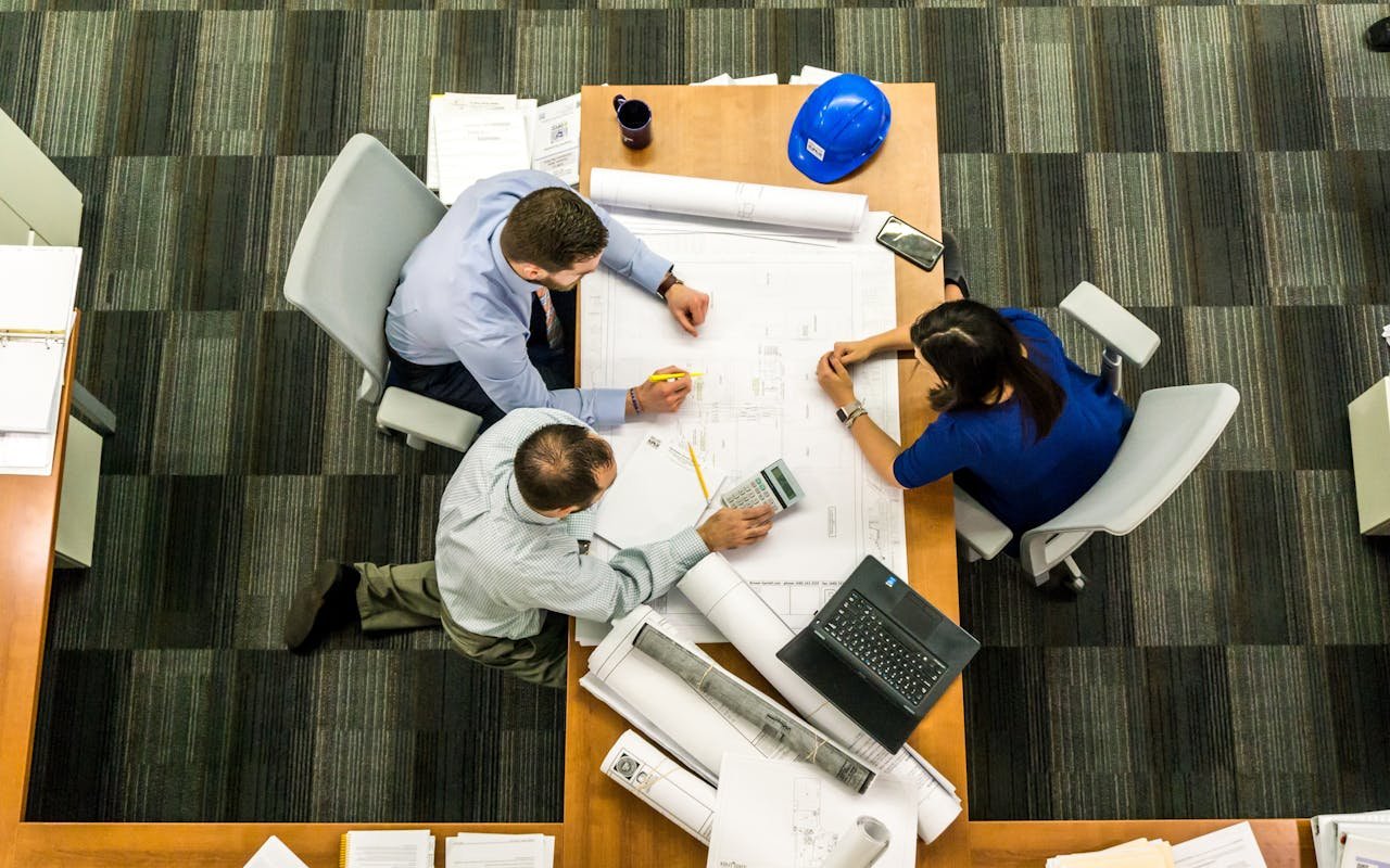 Services-02 Top view of a team working on construction plans in an office setting.