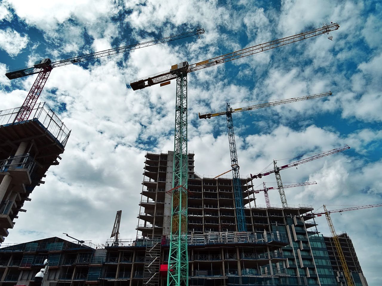 Services-01 Urban construction site with numerous cranes framing rising skyscrapers against a blue sky.